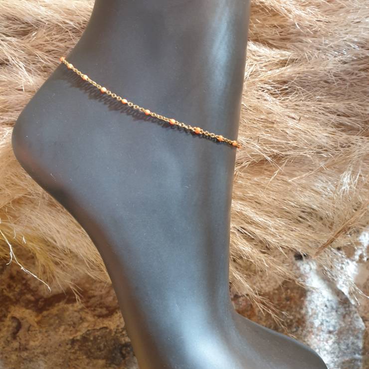 Chaîne bracelet de cheville doré perles émaillées orange, S'adapte à toute les chevilles grâce à sa chaînette d'extension.  Matière de la chaîne cheville acier inoxydable doré.