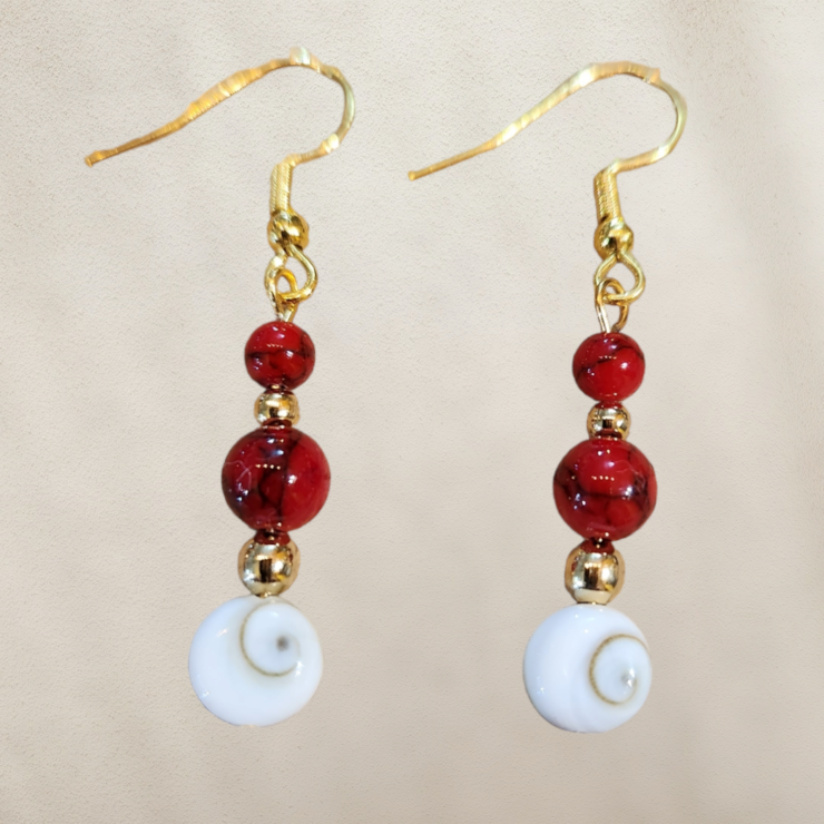 Boucles d'oreilles howlite rouge perles véritable, petites perles acier inoxydable doré puis orné d'un opercule appelé l'œil de sainte Lucie, porte bonheur  Confectionné à la main,  